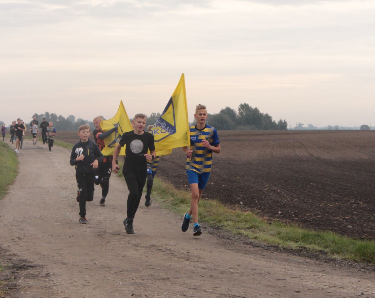 Bieg rozpoczął się w polu. Na zdjęciu młodzież ze sztandarem klubu GLKS Sokół Damasławek