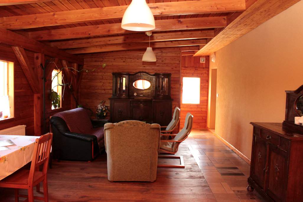 Pokój dzienny dla gości wypełnia ciepłe światło. To za sprawą dużej ilości drewna. Klimatu dodają też antyczne meble 